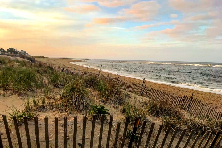 a wooden bench sitting on top of a sandy beach