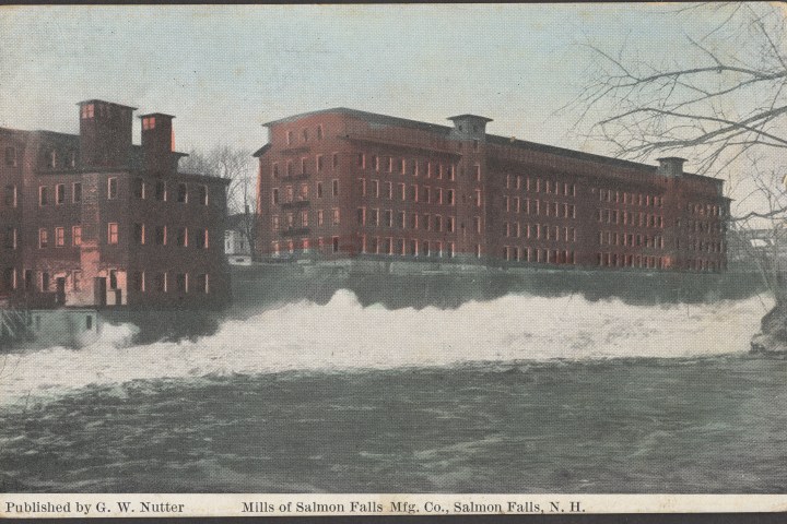 Historic brick mill building by a river with visible water flow.