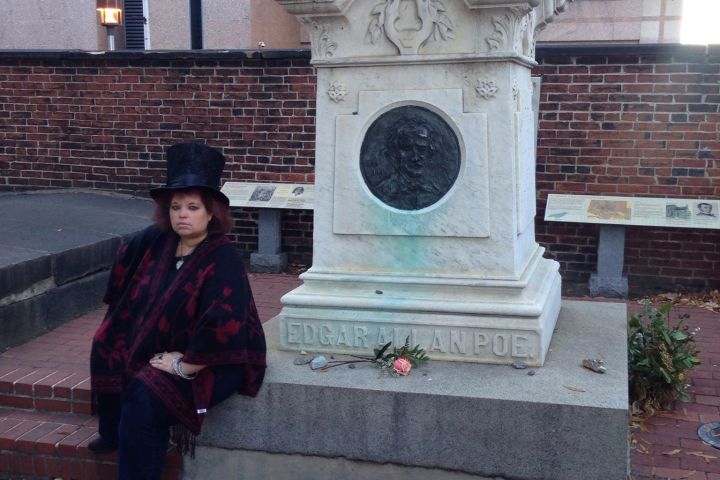 a person sitting on a sidewalk next to a brick wall