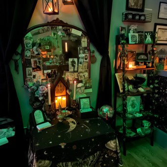 Decorative altar with candles, photos, and mystical items in a dimly lit room.