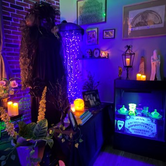 Spooky room with candles, Ouija board, and gothic decorations under purple lighting.