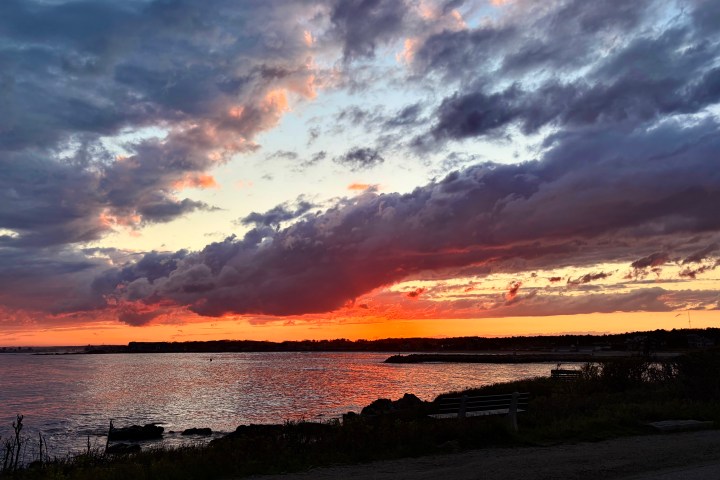 Dramatic sunset over a lake with colorful clouds and a dark shoreline.