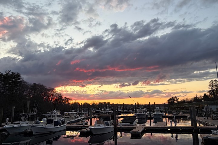 Boats docked at a marina during sunset with colorful clouds.